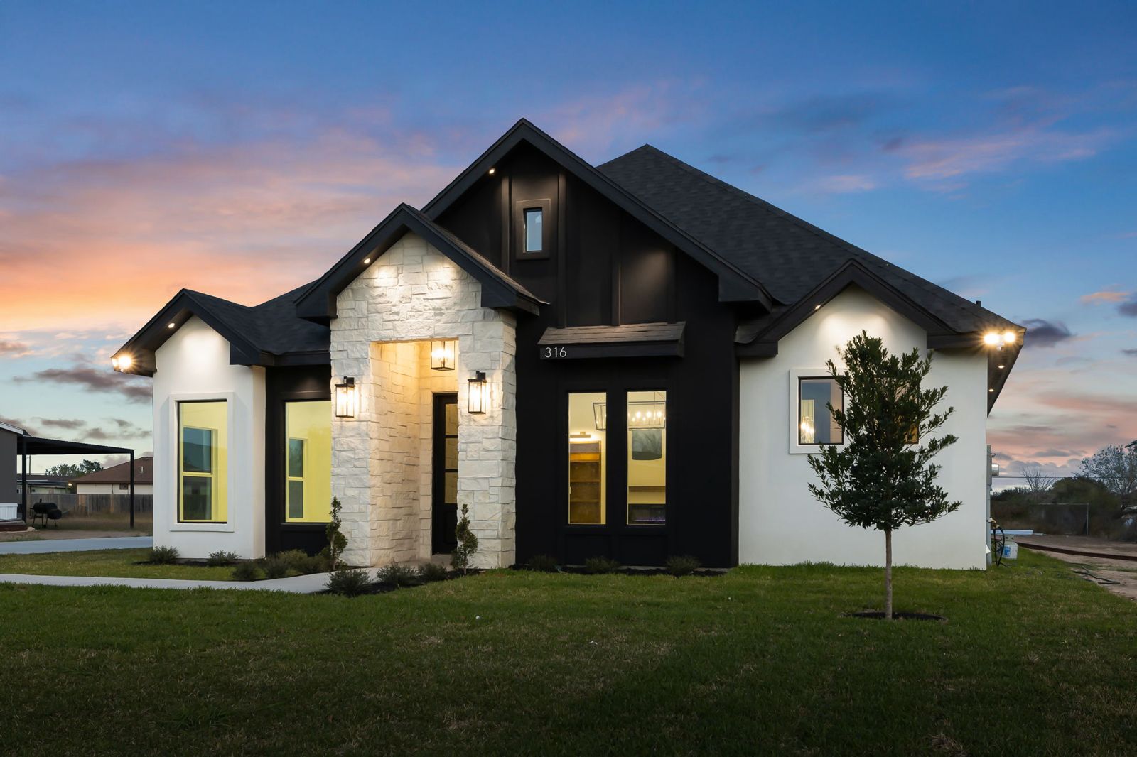 Corner view of the black and white stone exterior at dusk — The Black & Stone, a Kratos Construction custom home