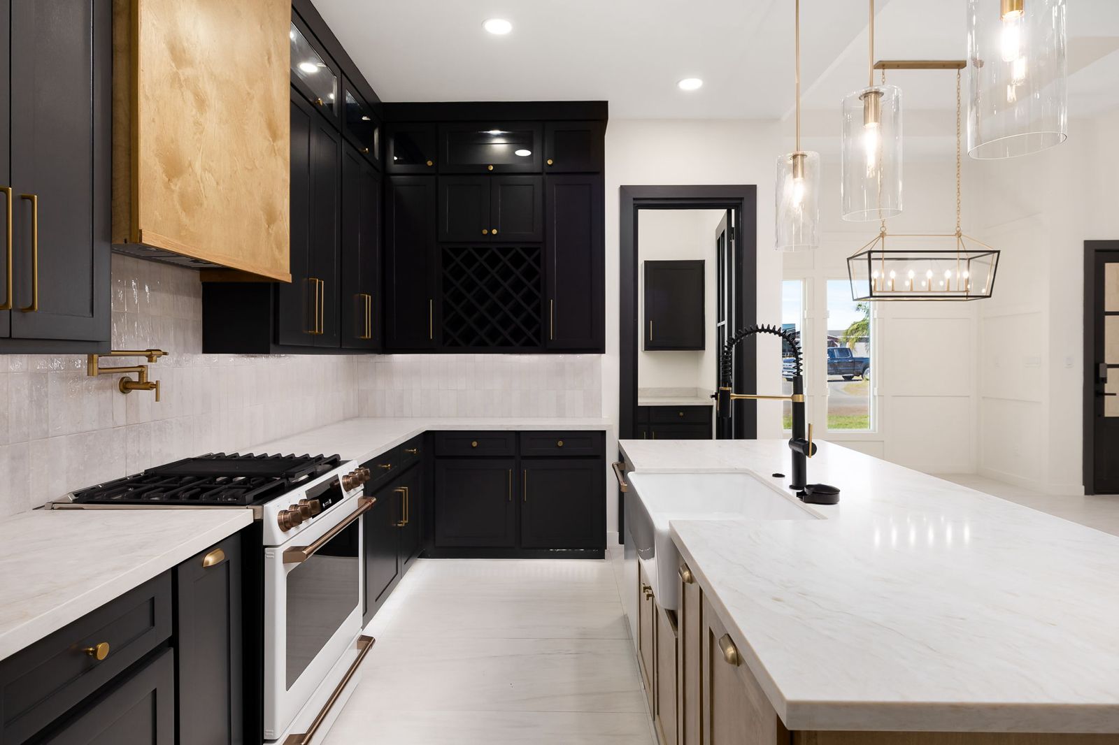 Chef's kitchen with black cabinetry, a walnut range hood, gas range and pot filler — The Black & Stone, a Kratos Construction custom home