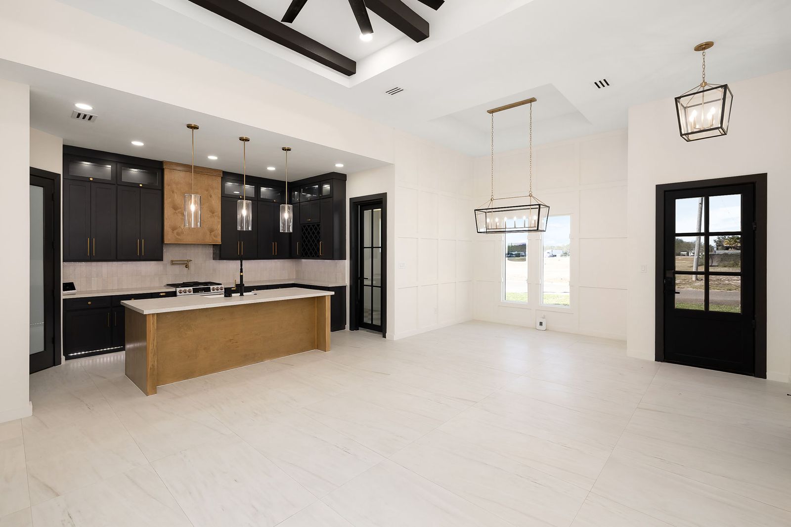 Open kitchen and dining area with black cabinetry and a natural-wood island — The Black & Stone, a Kratos Construction custom home