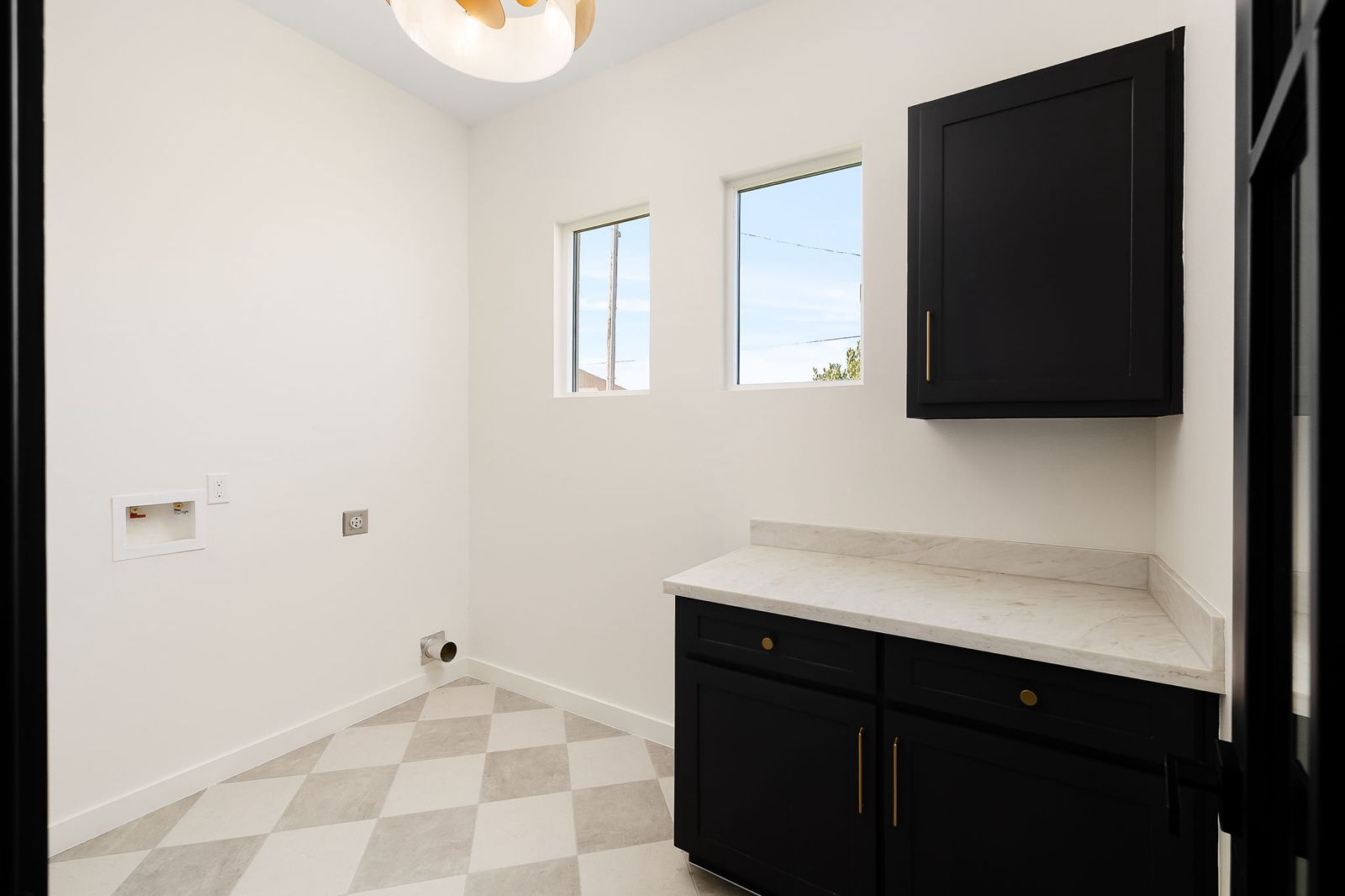 Laundry room with checkered tile and black cabinetry — The Black & Stone, a Kratos Construction custom home