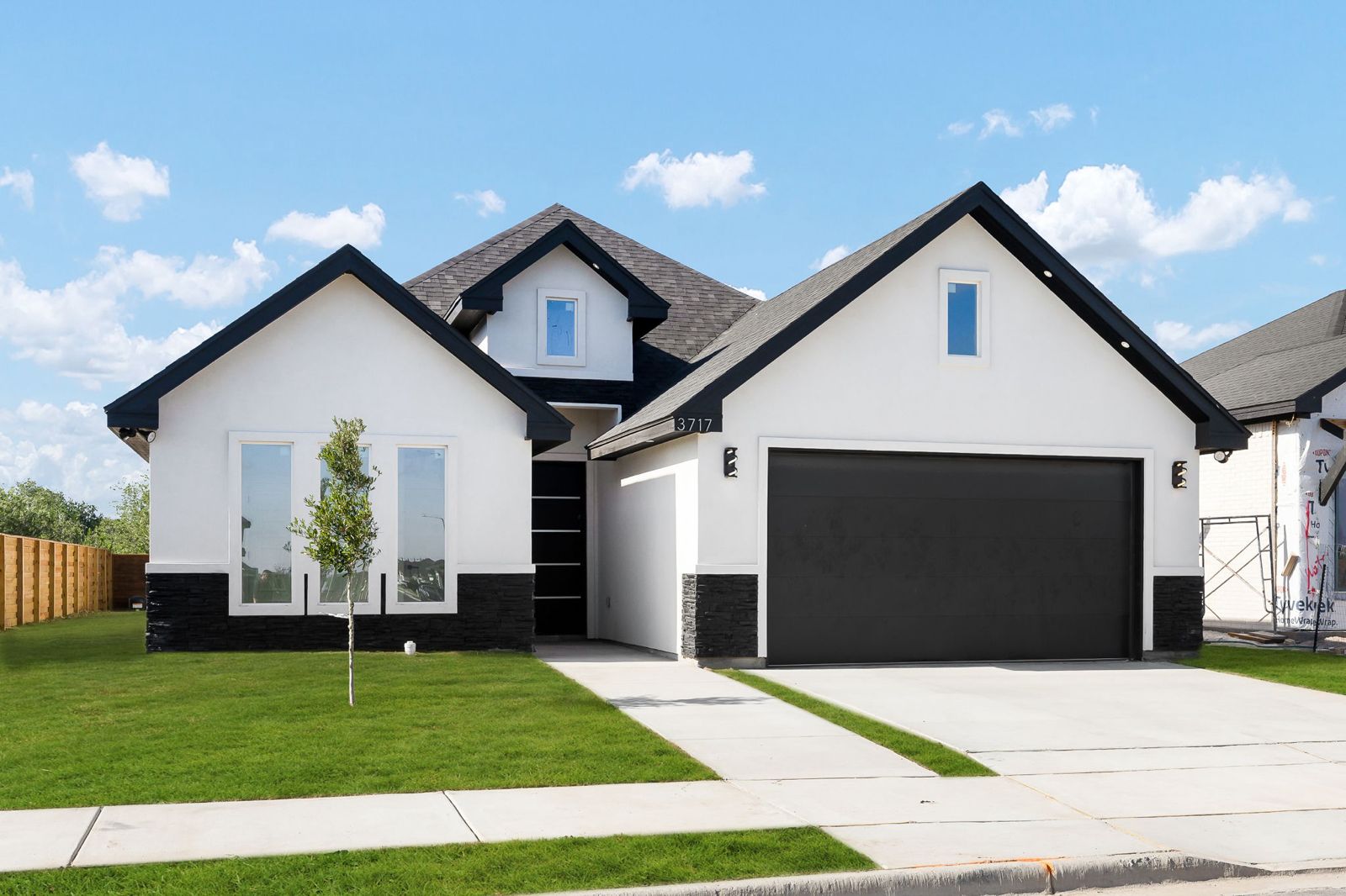 White stucco exterior with black trim, stacked-stone base and a two-car garage — The Black Trim, a Kratos Construction custom home