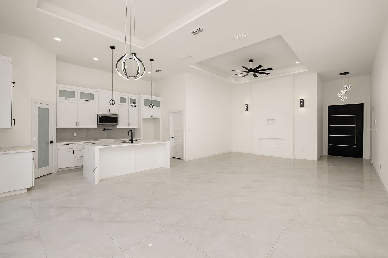 Open kitchen and living room with modern pendant lighting — The Black Trim, a Kratos Construction custom home