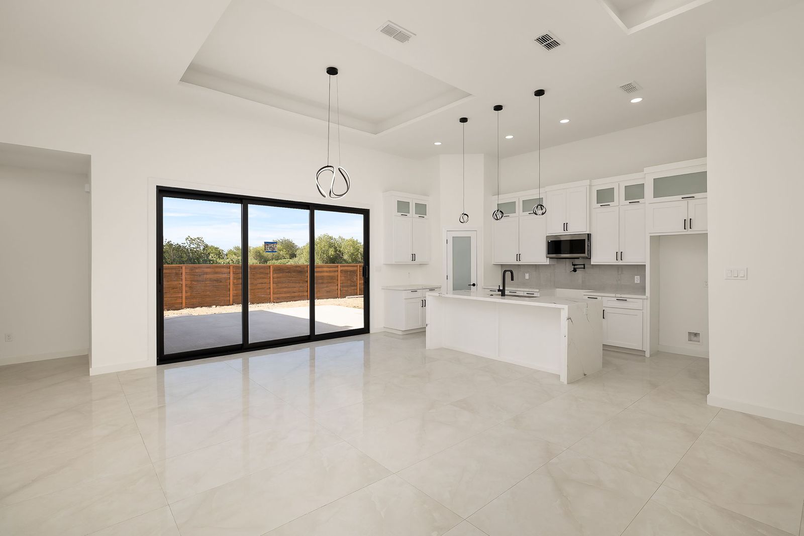Kitchen and living room with a wide sliding glass door to the backyard — The Black Trim, a Kratos Construction custom home