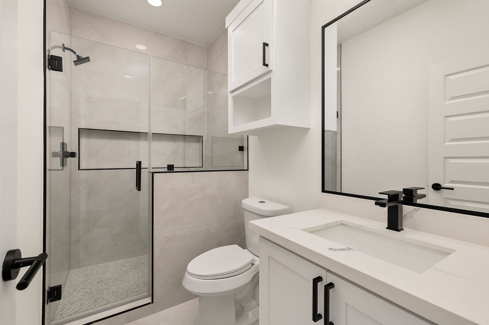 Bathroom with a glass walk-in shower and black fixtures — The Black Trim, a Kratos Construction custom home