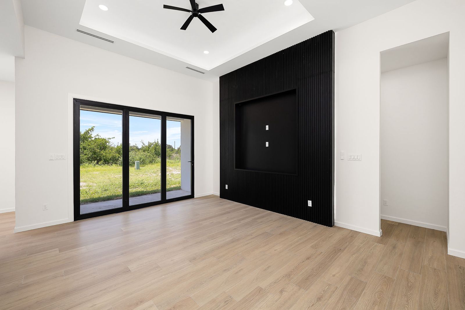 Living room with a black slat media wall and sliding glass doors — The Modern Farmhouse, a Kratos Construction custom home