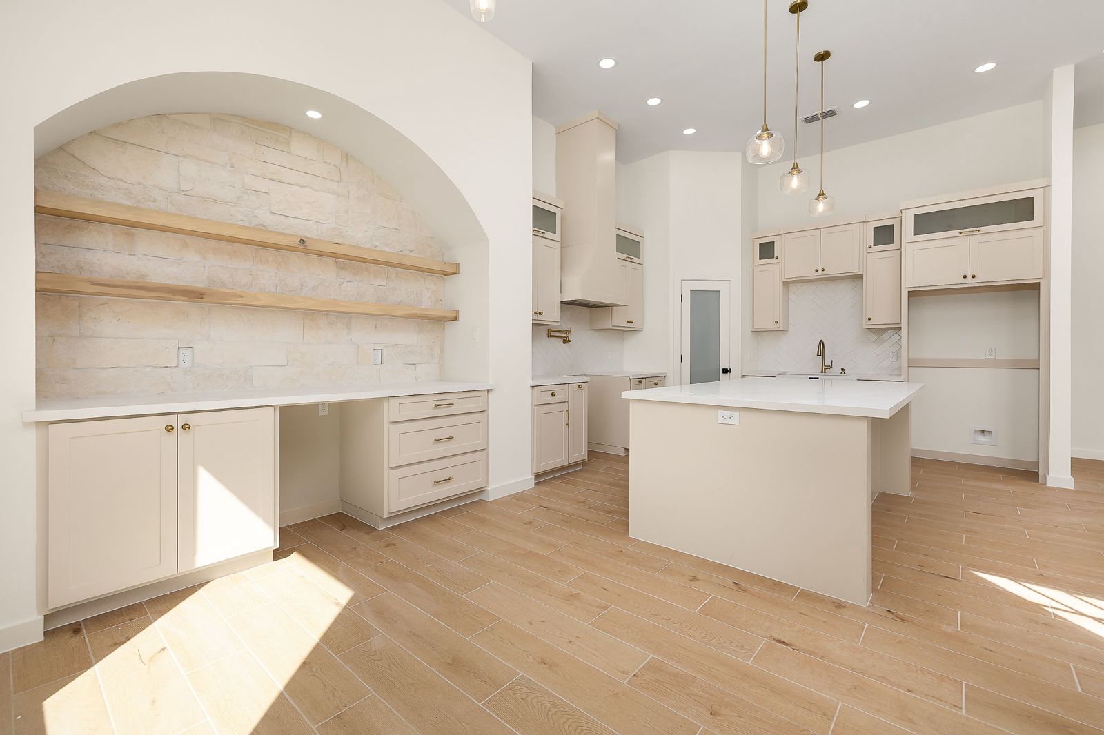 Arched stone niche with floating shelves beside the kitchen — The Hill Country, a Kratos Construction custom home
