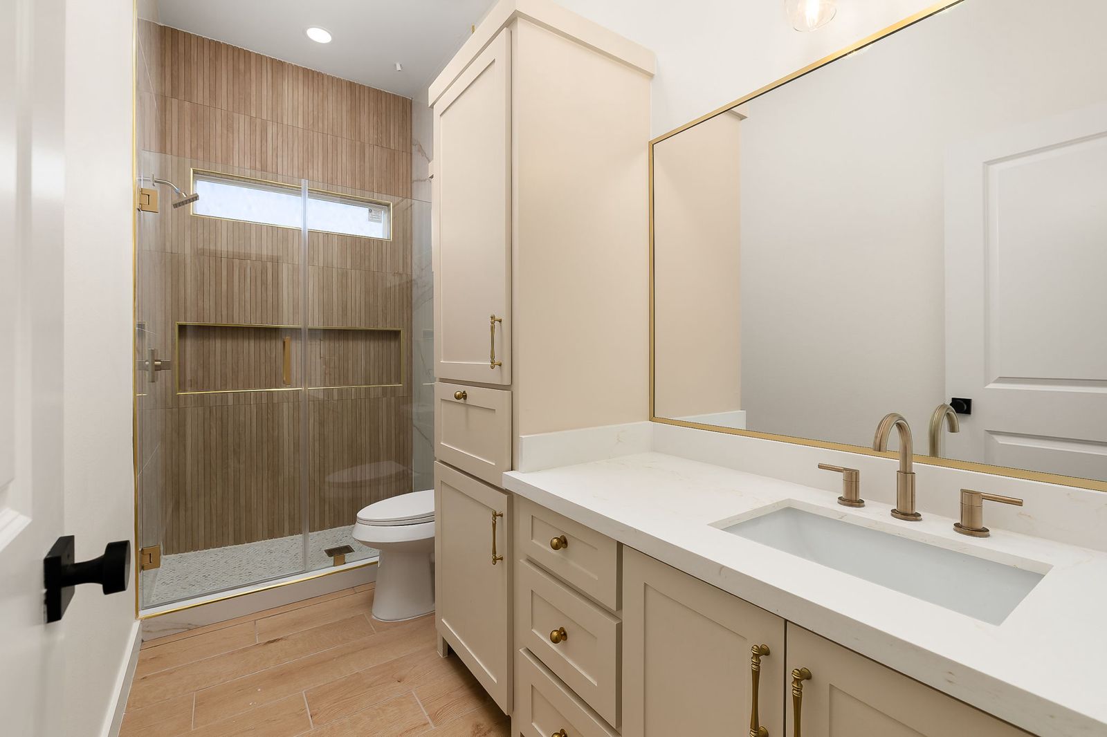 Bathroom with a gold-framed mirror and glass walk-in shower — The Hill Country, a Kratos Construction custom home