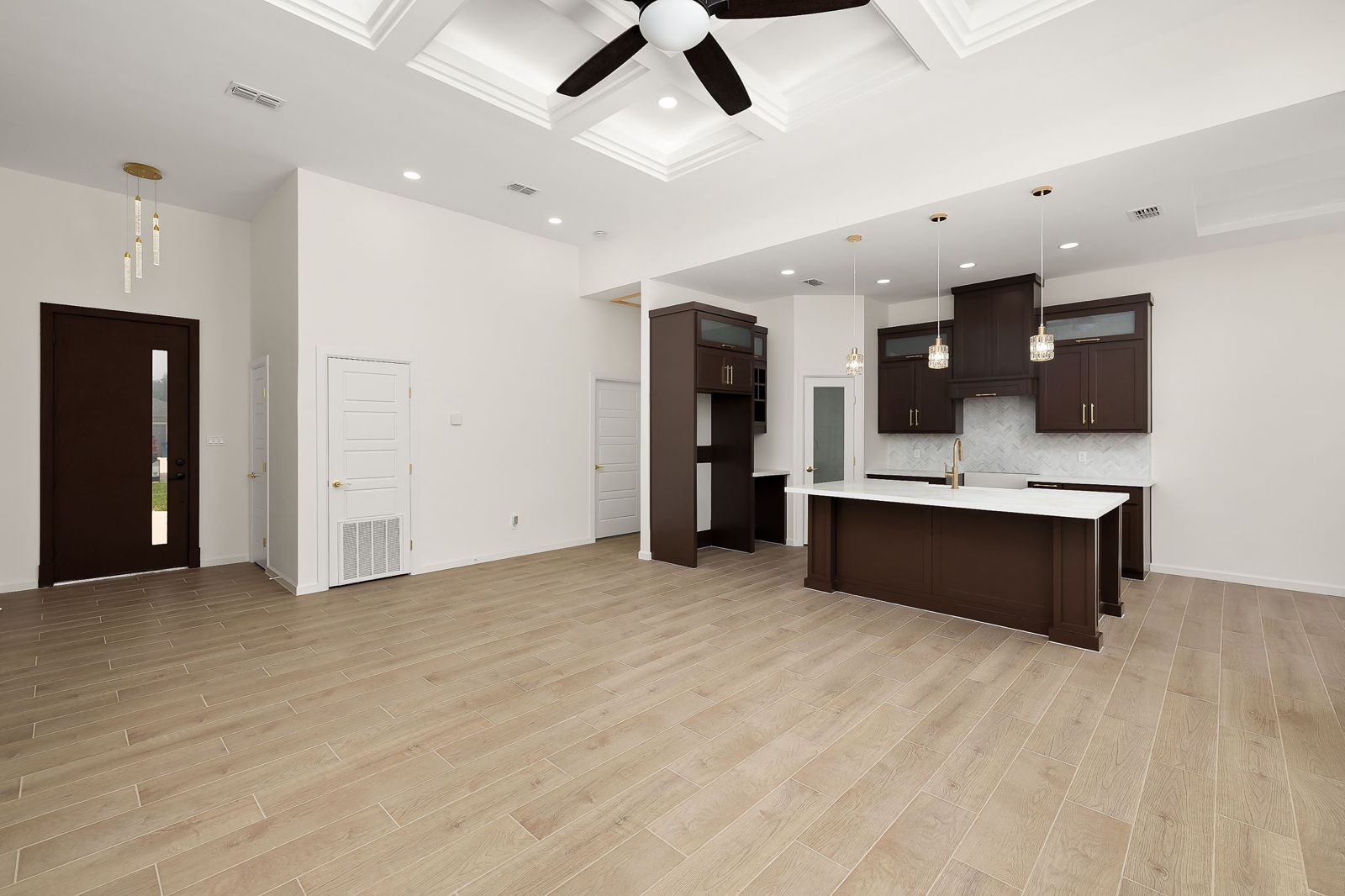 Open living room and kitchen with espresso cabinetry and wood-look floors — The Stone Column, a Kratos Construction custom home