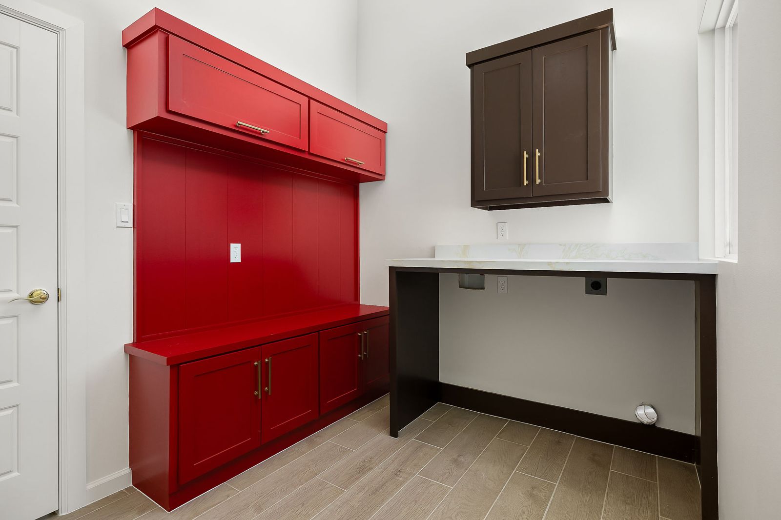 Mudroom with red lockers and bench plus a built-in desk — The Stone Column, a Kratos Construction custom home