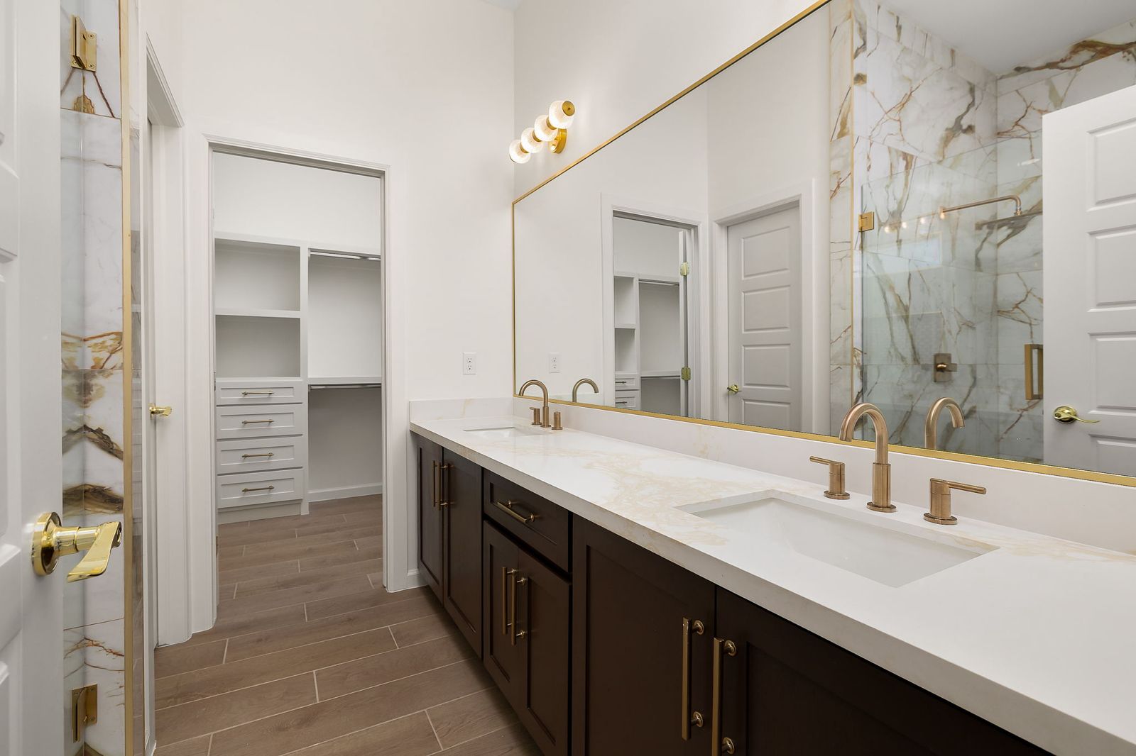 Primary bathroom with an espresso vanity and gold-framed mirror — The Stone Column, a Kratos Construction custom home