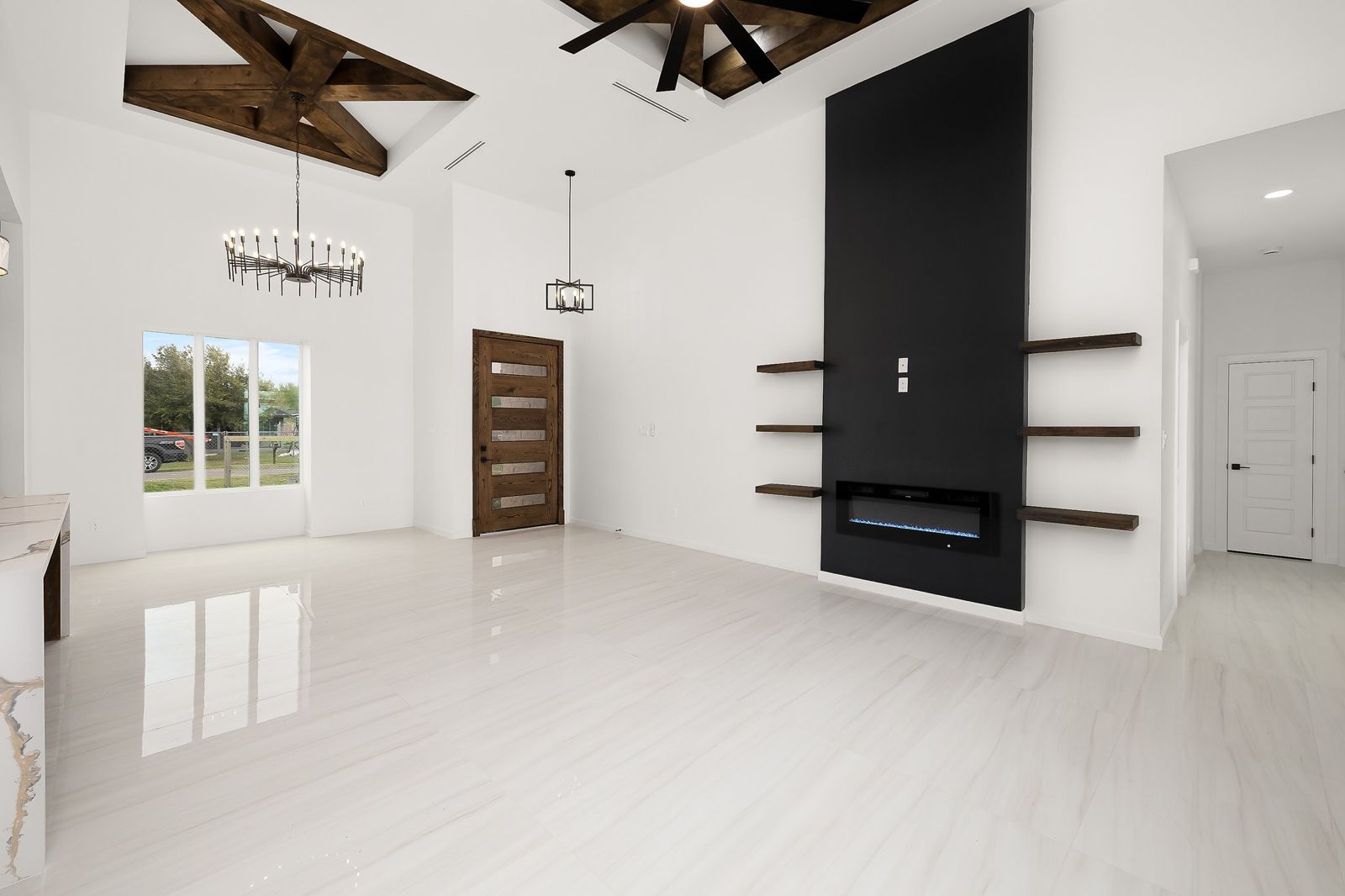 Living room under exposed timber beams with a black fireplace wall and floating shelves — The Stone & Timber, a Kratos Construction custom home