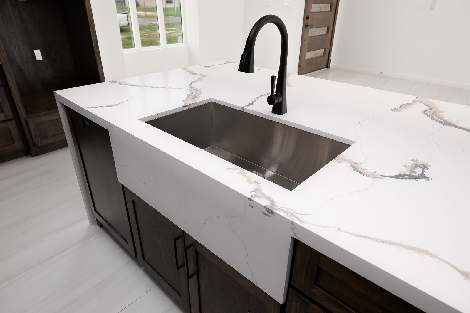 Quartz waterfall island with an undermount sink and matte black faucet — The Stone & Timber, a Kratos Construction custom home