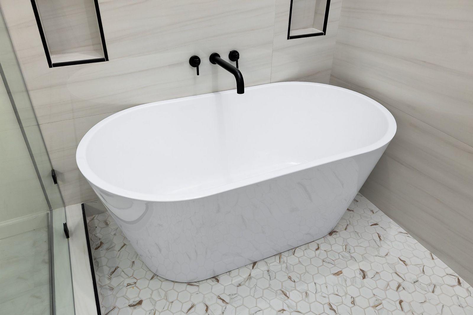 Freestanding soaking tub with a wall-mounted matte black faucet — The Stone & Timber, a Kratos Construction custom home