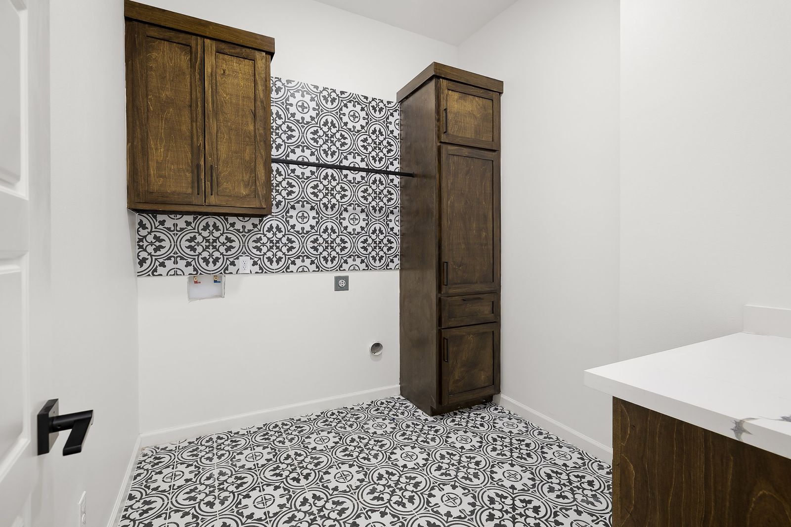 Laundry room with patterned cement-look tile and stained-wood cabinets — The Stone & Timber, a Kratos Construction custom home