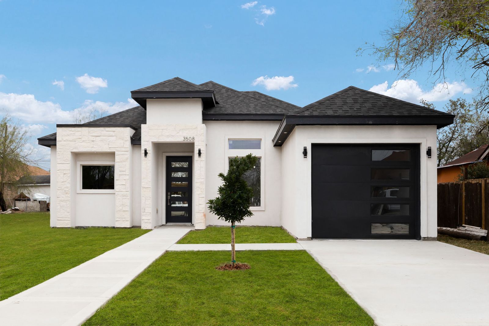 White stucco and stone exterior with a black glass-panel garage door — The Stucco & Stone, a Kratos Construction custom home
