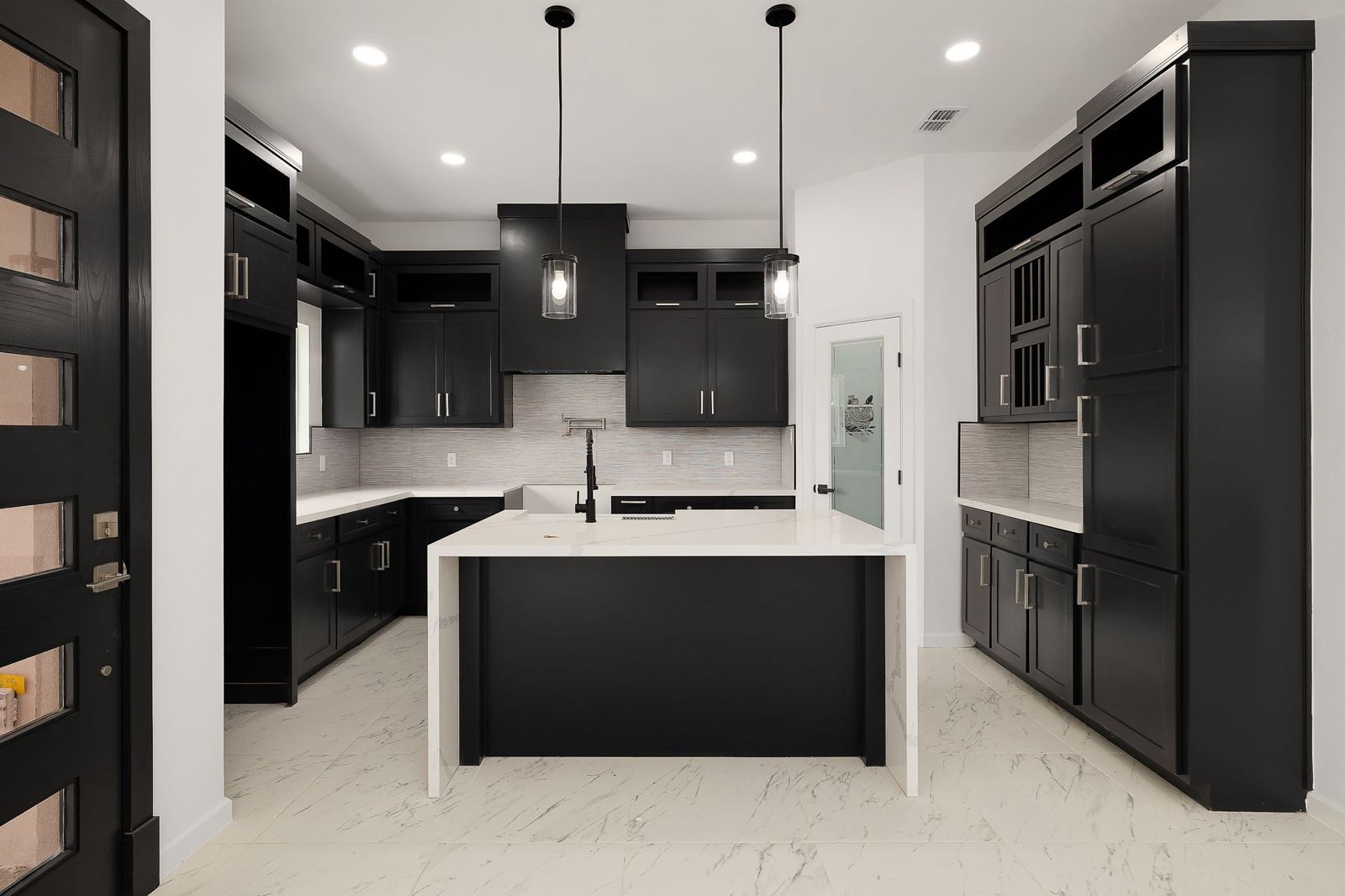 Kitchen with black shaker cabinetry and a waterfall island — The Stucco & Stone, a Kratos Construction custom home