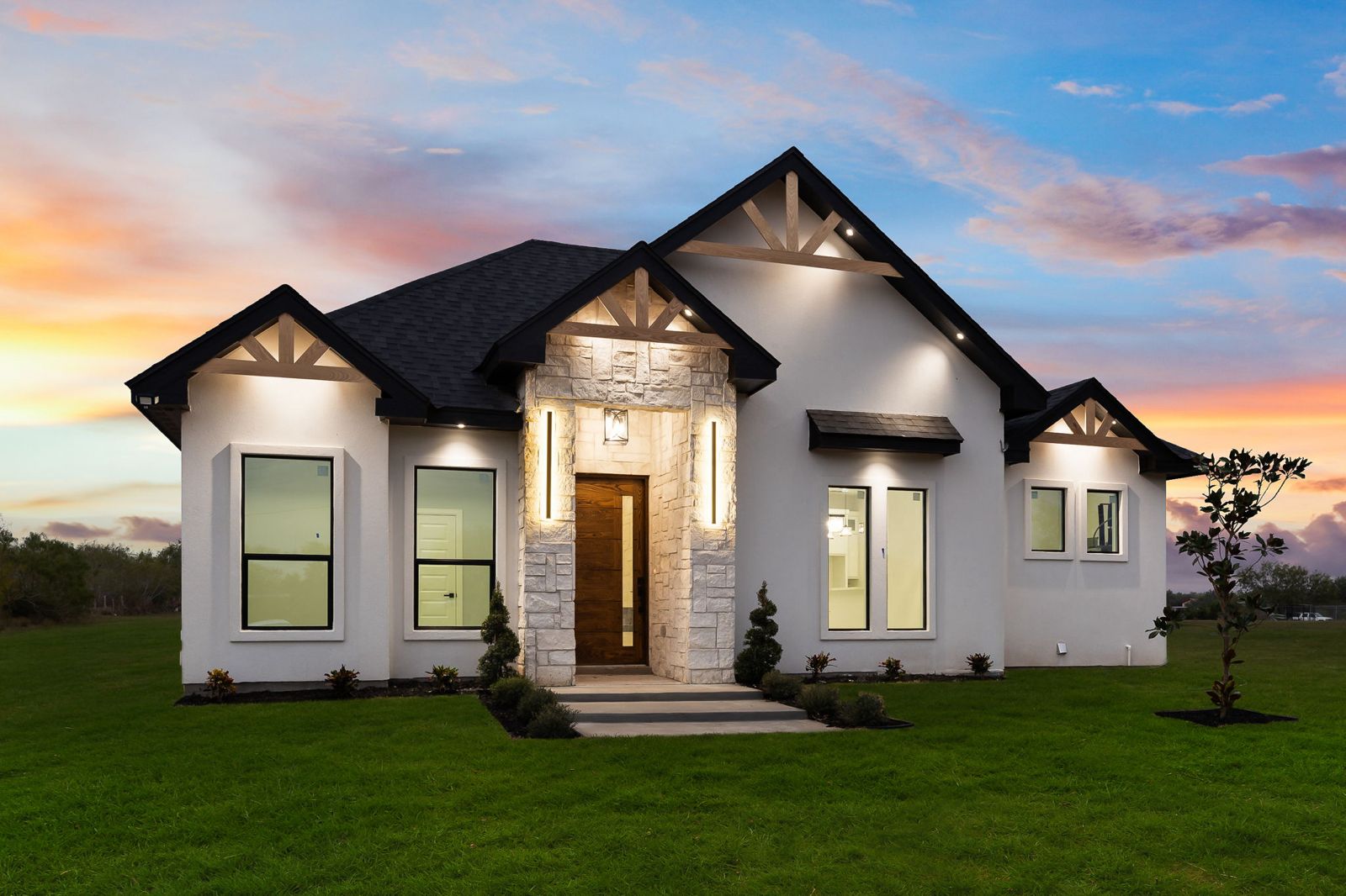 Dusk exterior with a stone entry, cedar gable trusses and a wood front door — The Timber Gable, a Kratos Construction custom home