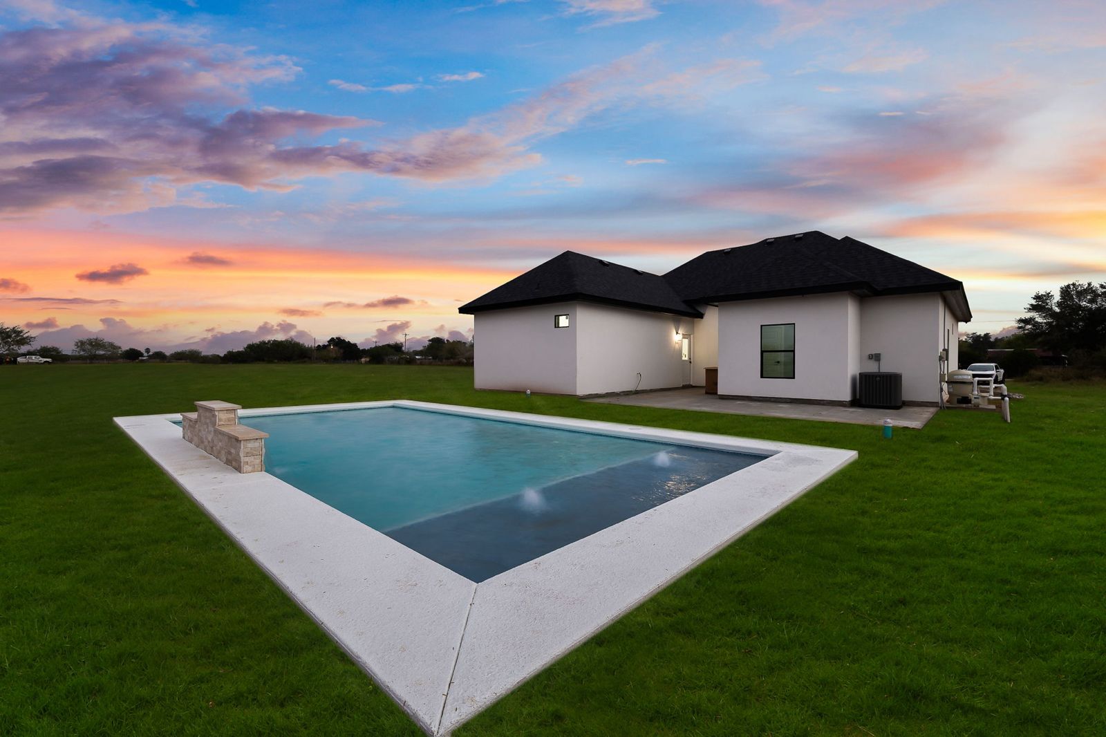 Backyard pool with a stone water feature at sunset — The Timber Gable, a Kratos Construction custom home