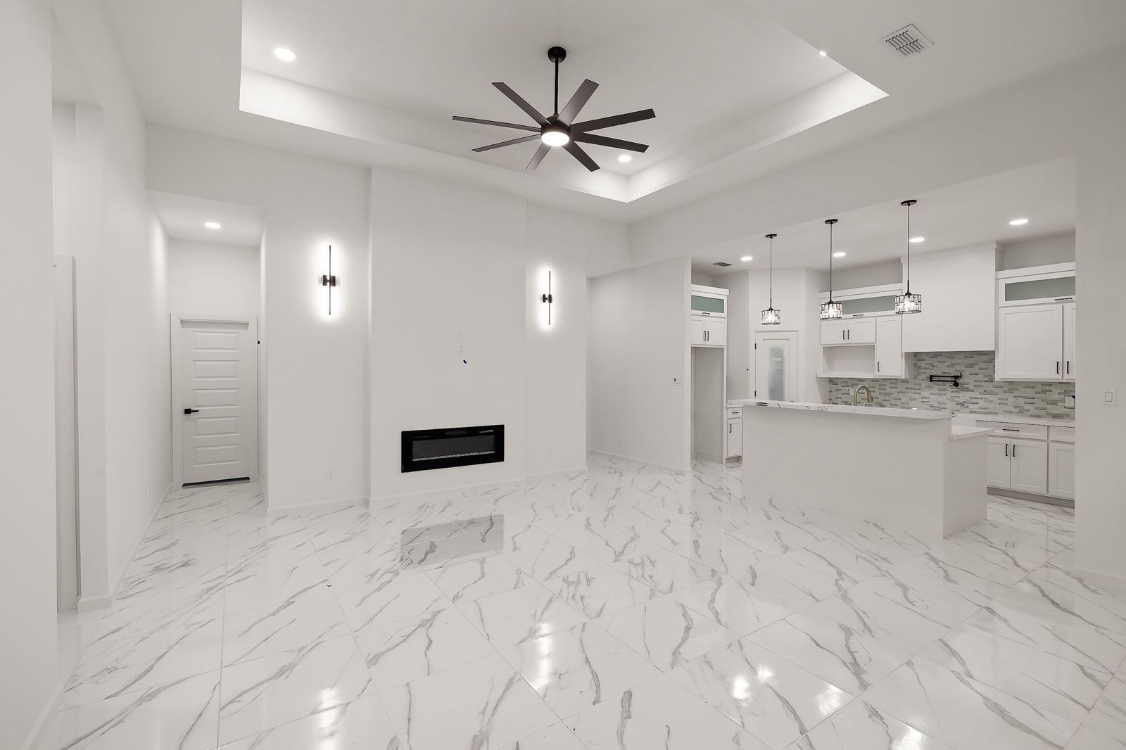 Living room with a linear fireplace, open kitchen and marble-look tile floors — The Timber Gable, a Kratos Construction custom home