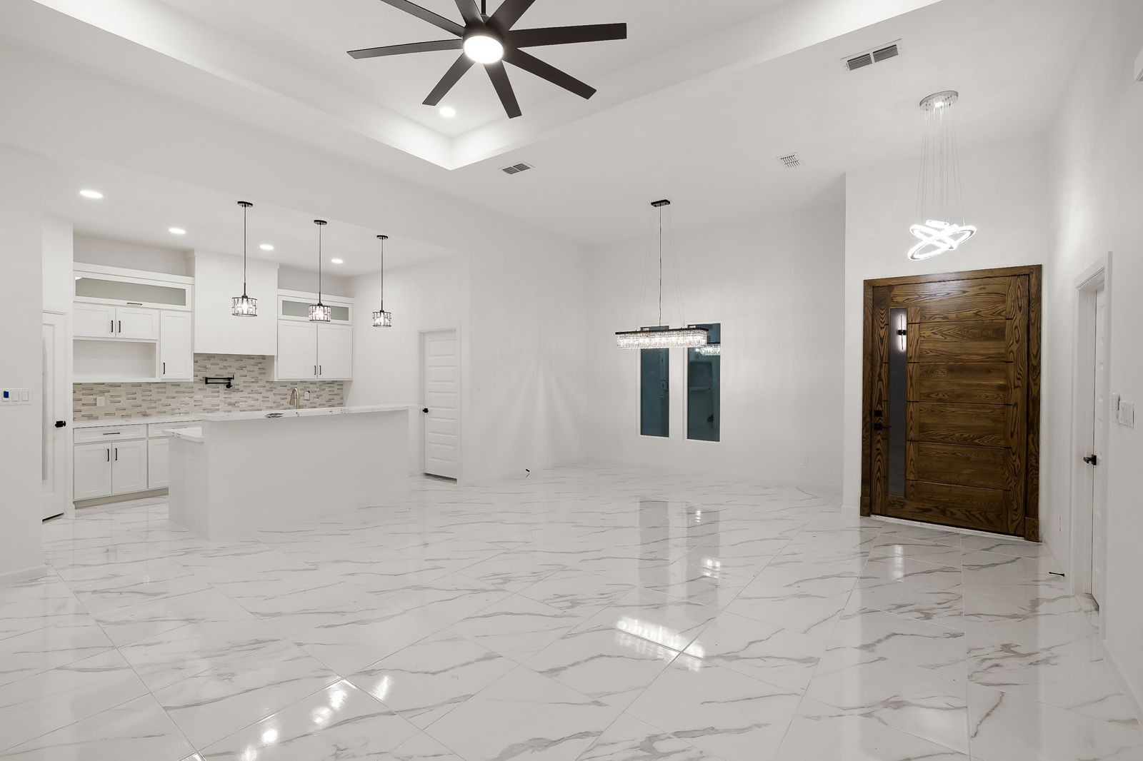 Entry with a wood pivot-style front door, dining area and kitchen — The Timber Gable, a Kratos Construction custom home