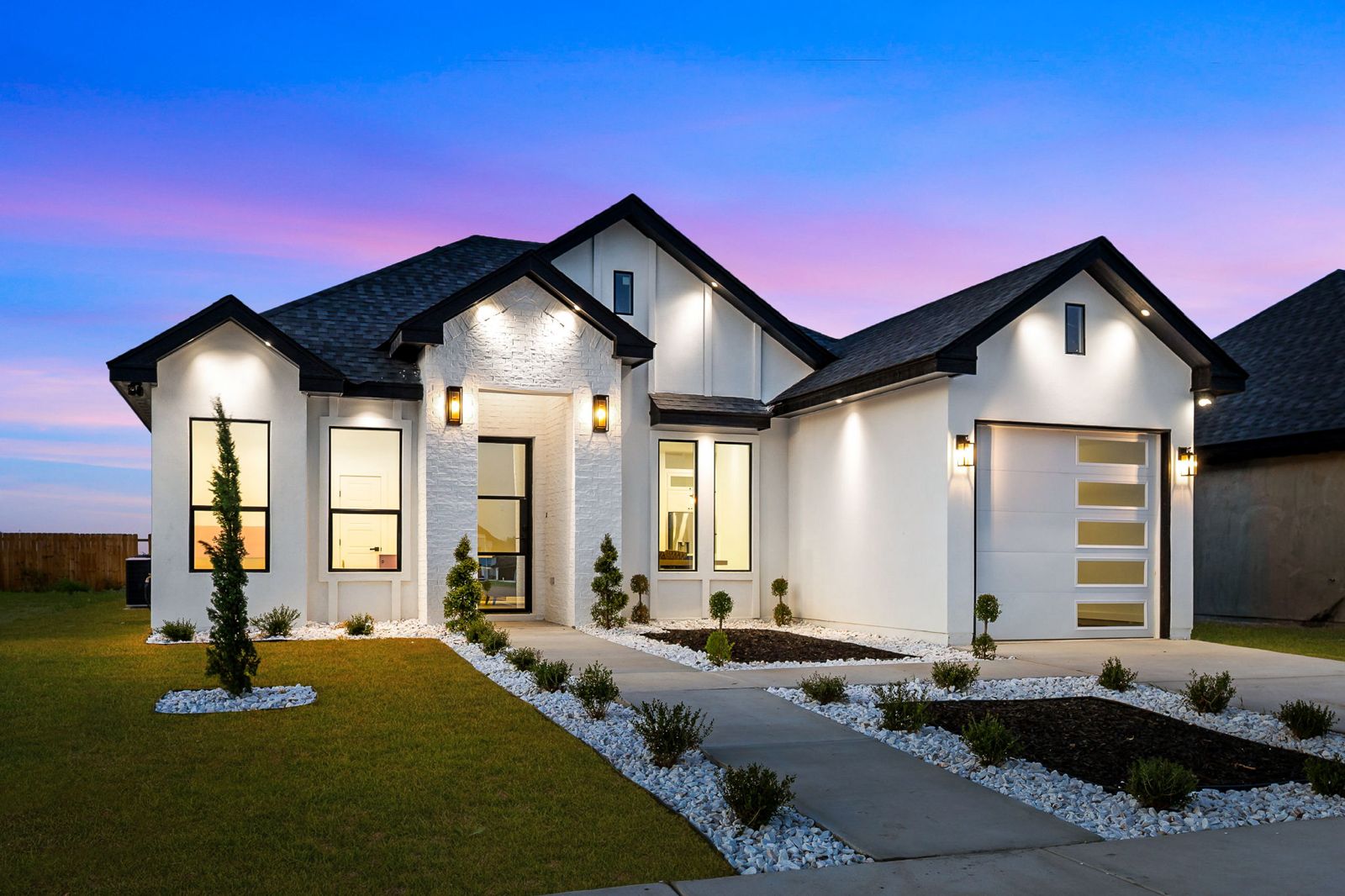 White brick exterior at dusk with black-framed windows and xeriscape landscaping — The White Brick, a Kratos Construction custom home
