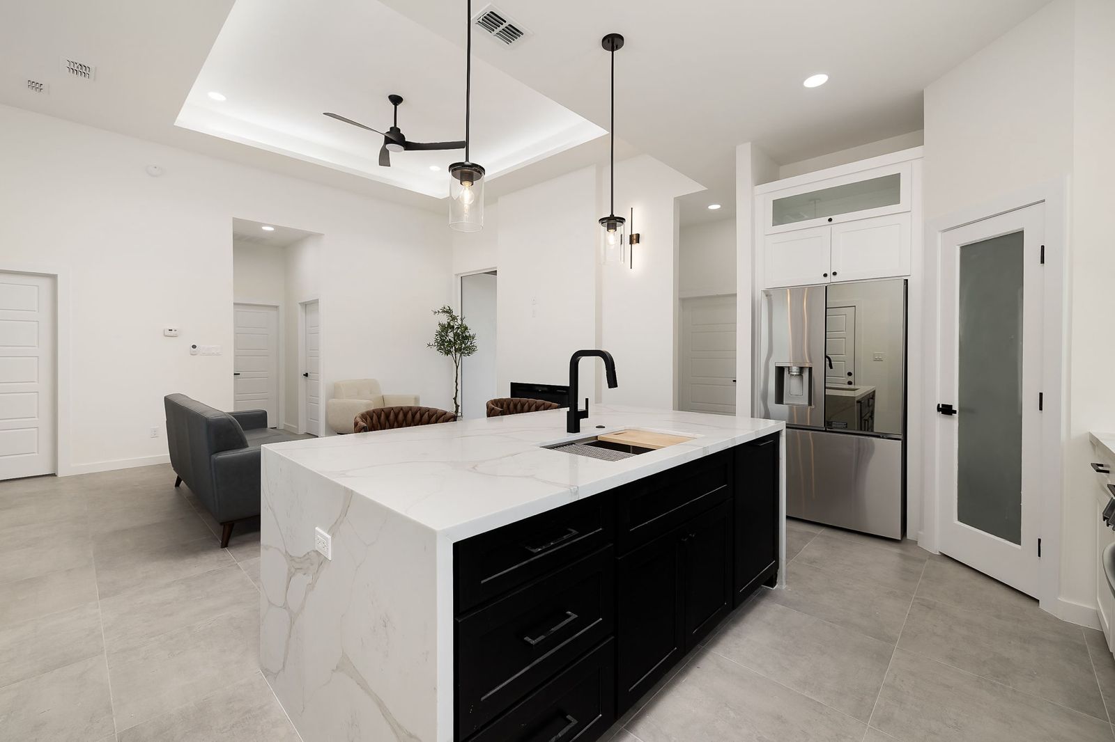 Kitchen with a black waterfall island and stainless appliances — The White Brick, a Kratos Construction custom home