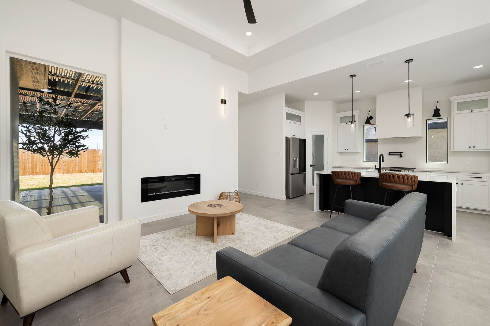 Living room open to the kitchen and covered patio — The White Brick, a Kratos Construction custom home