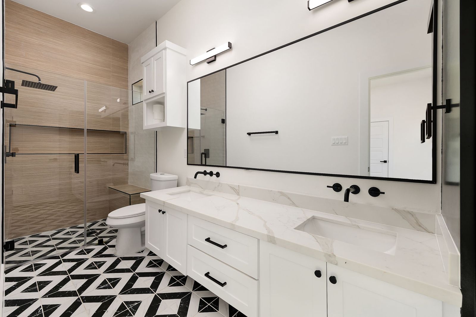 Bathroom with black-and-white patterned tile and a glass walk-in shower — The White Brick, a Kratos Construction custom home